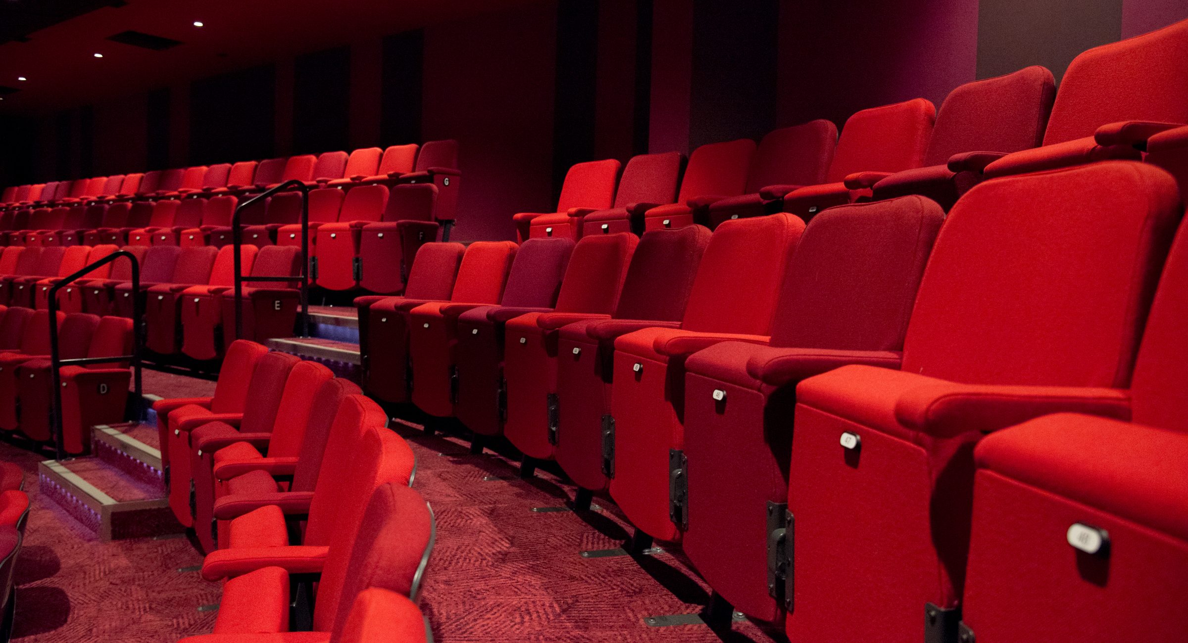A shot of empty red auditorium chairs.