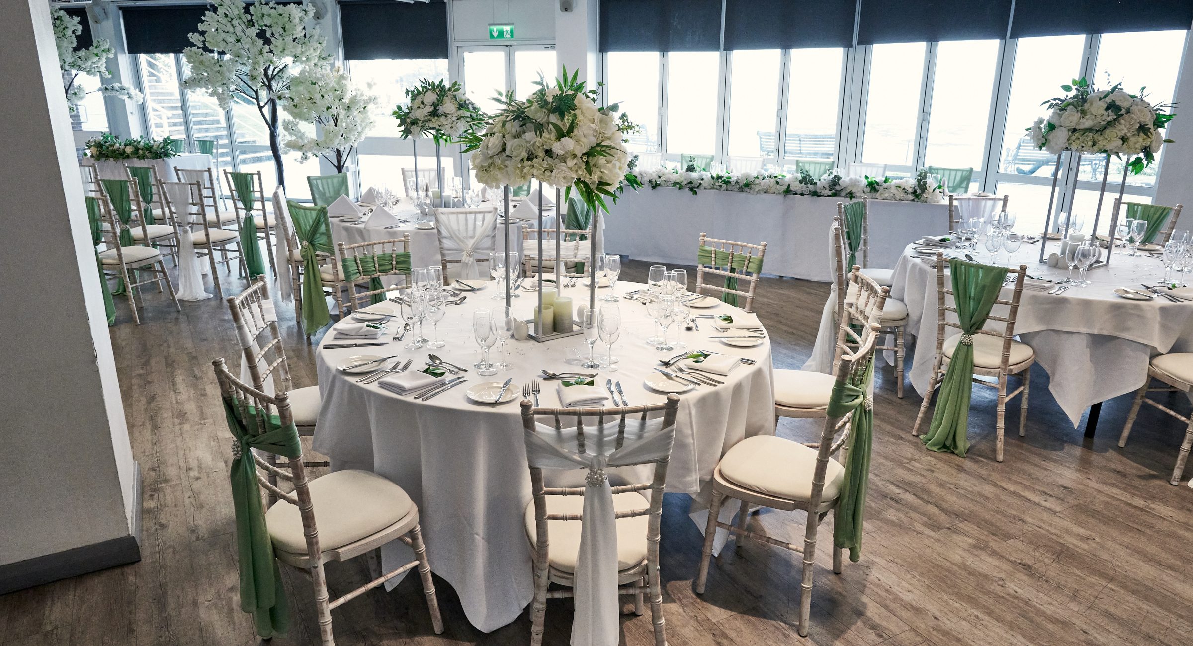 A beautifully dressed room of elegantly decorated fully laid banqueting tables and chairs with florals and linens.