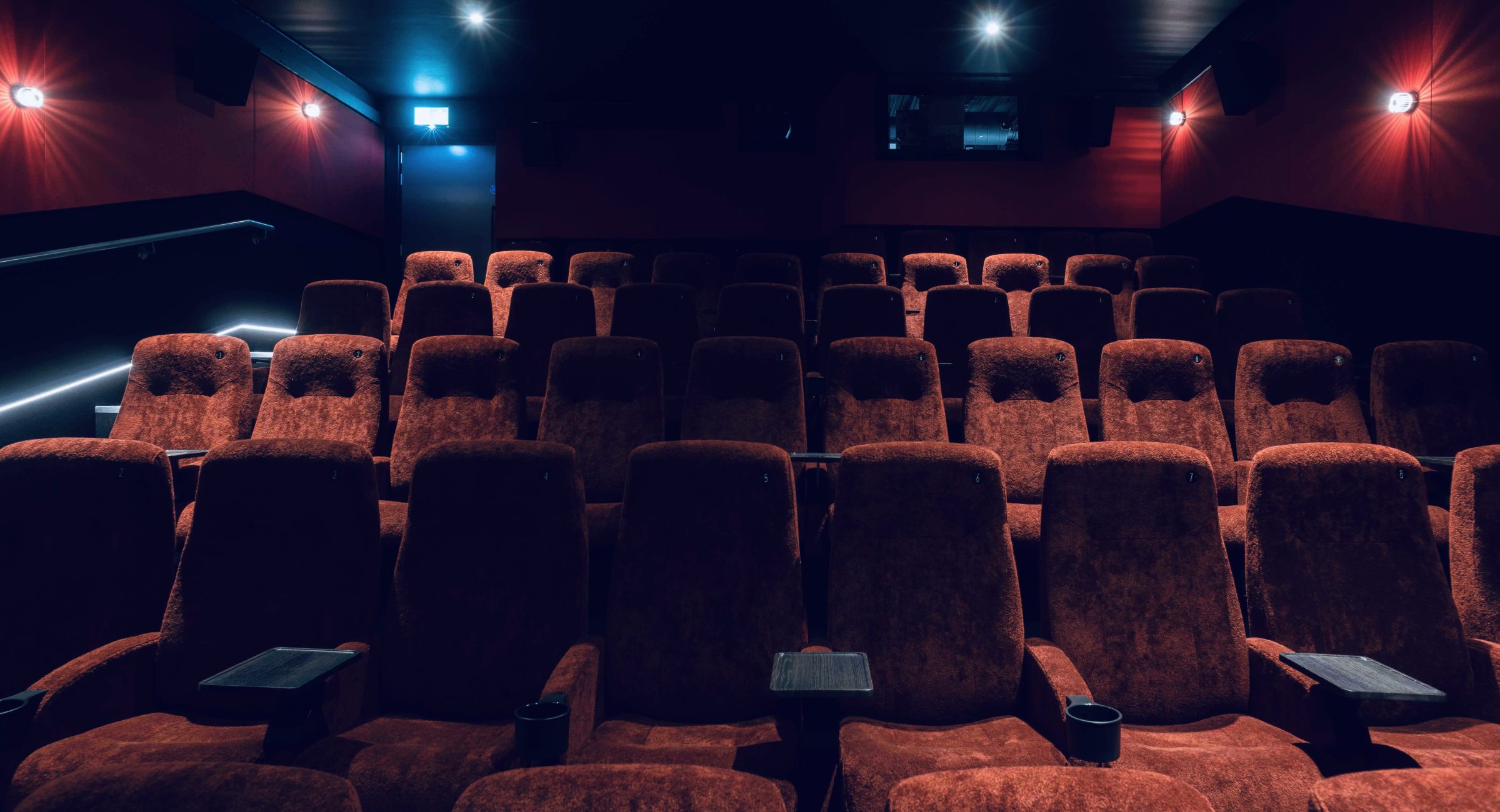 Dark red cinema chairs with red beacon lights on the walls.