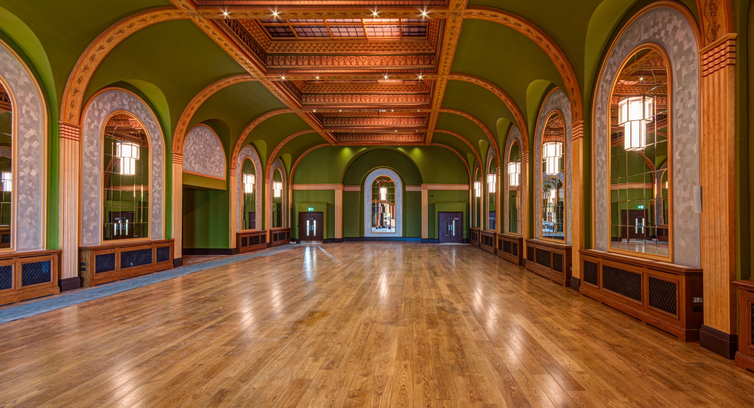 A beautiful art deco ballroom with glossy polished floors, green walls, domed ceilings and mirrors.
